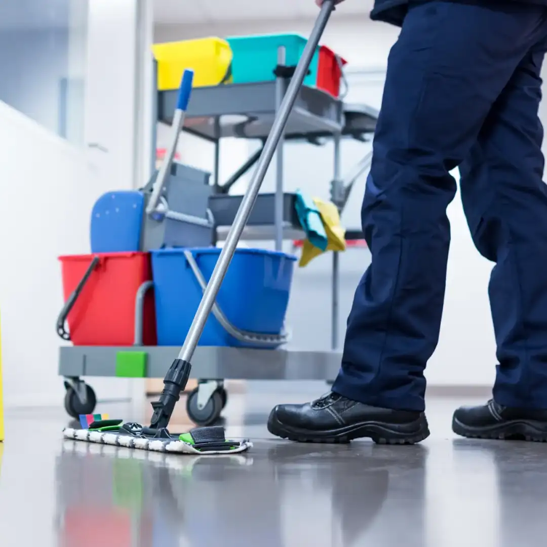 Janitor mopping office floor with cleaning supplies, showcasing essential office cleaning tips.